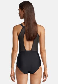 Maillot de bain une pièce noir avec un dos en mesh, des bretelles racerback et un décolleté arrière plongeant. Texture lisse et design ajusté.