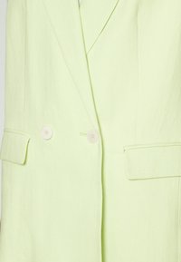 Jasnozielony dwurzędowy blezer wykonany z teksturowanej tkaniny, z dwoma guzikami i skośnymi bocznymi kieszeniami. Charakterystyczny kołnierz.