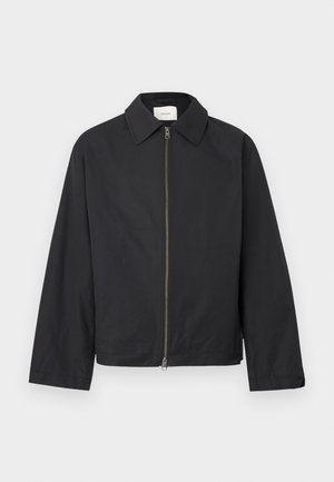 Veste noire à fermeture éclair, manches longues et col pointu, présentée à plat sur un fond blanc.