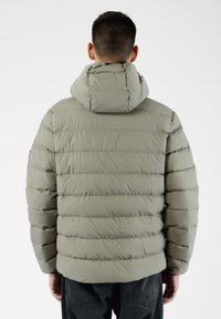 Giacca puffer grigia chiara con cappuccio, caratterizzata da sezioni trapuntate e polsini elasticizzati. Materiale liscio e resistente all'acqua senza etichette visibili.