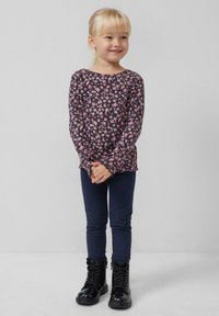 Lange mouw, donker bloempatronen shirt met een ronde hals, gecombineerd met donkerblauwe leggings en zwarte gepatineerde enkelschoenen.