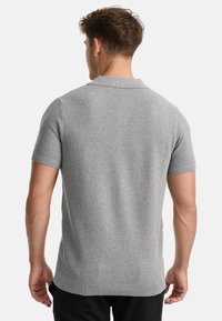 Camisa polo de manga corta en gris jaspeado con un acabado texturizado, puños acanalados y un cuello clásico. La vista posterior muestra un corte entallado.