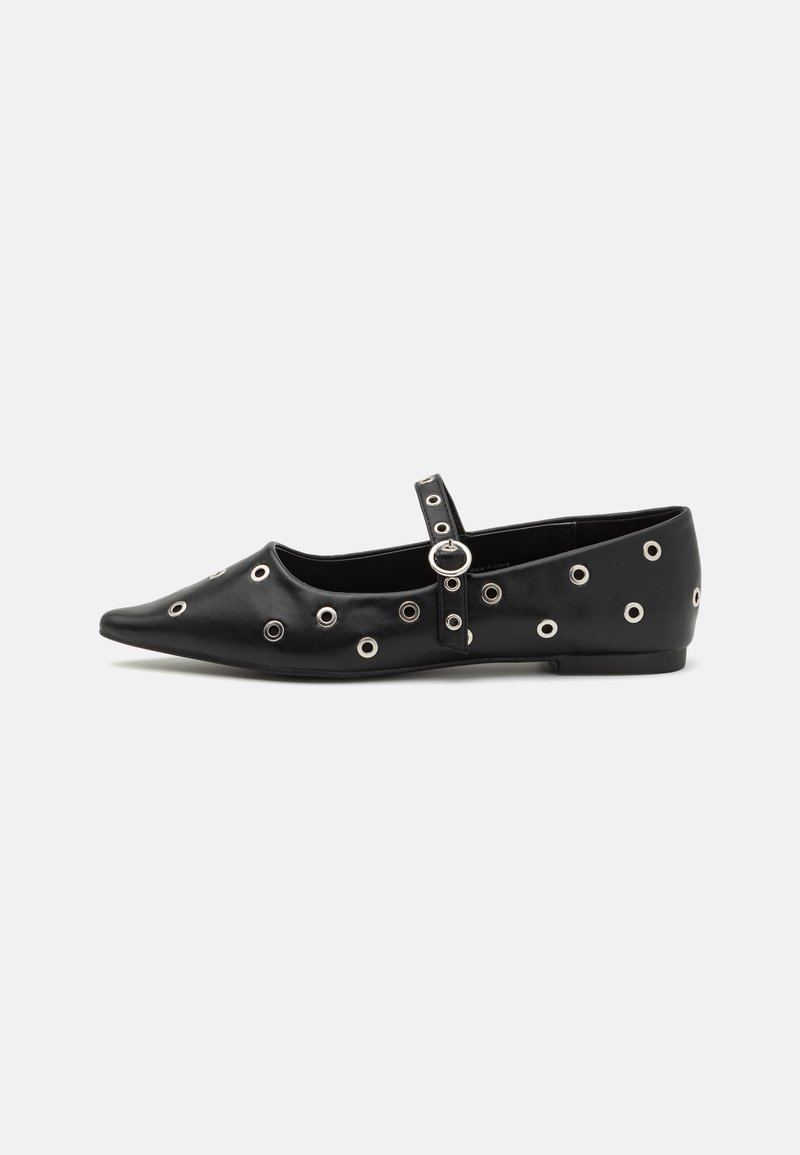 Chaussure plate en cuir noir avec un orteil pointu, ornée d'œillets en argent décoratifs et d'une sangle ajustable autour de la cheville.