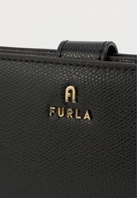 Black textured leather handbag with a gold-tone "FURLA" logo. Features a sleek design and sturdy stitching. Compact and elegant.