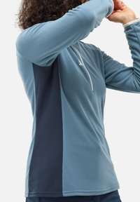 Pull-over à manches longues en bleu clair et bleu marine, doté d'une fermeture éclair quart de zip, d'un tissu texturé et d'un design à panneaux latéraux contrastés.