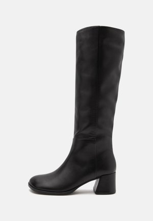 Botte en cuir noire montant jusqu'au genou avec talon bloc, bout arrondi et finition lisse, vue de profil sur fond blanc.