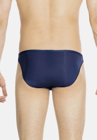 Marineblaue Badehosen aus glattem, dehnbarem Material mit enganliegendem Design und niedrigem Bund, ausgestattet mit minimalen Nähdetails.