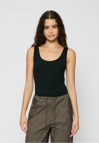 Black, sleeveless bodysuit with a scoop neckline, made of smooth fabric; styled with loose, olive green cargo pants featuring side pockets.