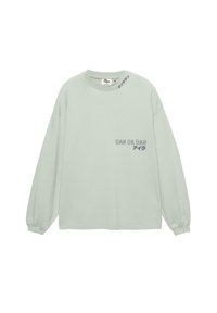 Light green long-sleeve sweatshirt made of cotton, featuring a rounded neck, dropped shoulders, and printed text on the front and sleeve.