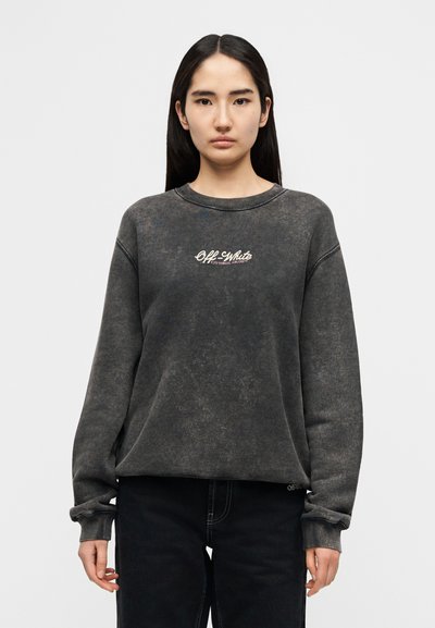 Σκούρο γκρι φούτερ με υφή, με λευκό λογότυπο "Off-White" στο στήθος και ριμπ μανσέτες. Φορεμένο με μαύρο παντελόνι.