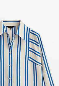 Camicia a maniche lunghe con colletto ampio, base crema e righe blu verticali e orizzontali sul davanti e sulle maniche.