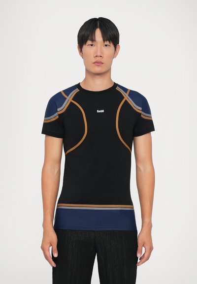 Camiseta atlética negra con acentos en navy y naranja, ajuste ceñido, cuello redondo y logo en el centro. Textura suave.