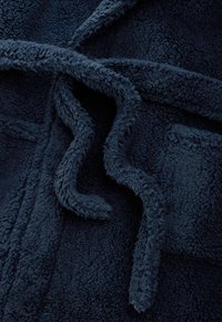 Nahaufnahme von dunkelblauem weichem Fleece-Stoff mit sichtbarer Struktur und gebundenen Kordelschlaufen.