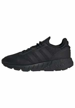 Baskets Adidas noires avec tige en mesh, trois bandes emblématiques sur le côté, semelle épaisse texturée et fermeture à lacets.