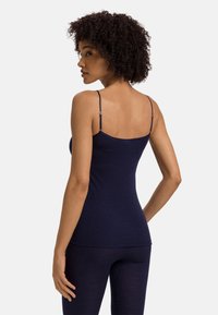 Námořnická modrá těsně padnoucí tílko s tenkými nastavitelnými ramínky, hladkou texturou a zaobleným výstřihem, doplněné o ladící kalhoty.