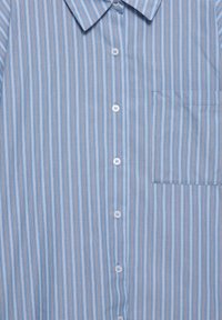 Camicia azzurra chiara con bottoni, decorata da sottili righe verticali in diverse sfumature di blu e arancione, colletto strutturato e taschino sul petto.