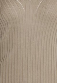 Beżowy sweter dzianinowy z pionowym prążkowaniem i dekoltem w kształcie V. Materiał wydaje się miękki, ma teksturowane, lekkie wykończenie.