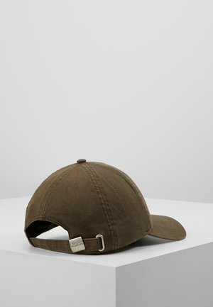 Casquette de baseball marron avec sangle métallique ajustable, présentée sur une surface blanche devant un fond gris clair uni.