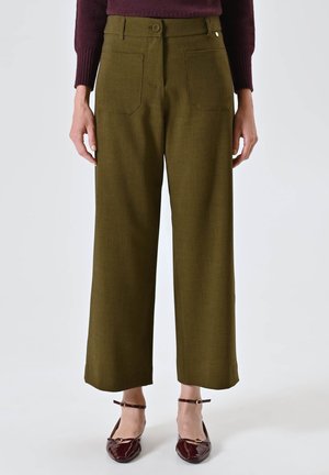 Pantaloni a gamba larga verde oliva realizzati in tessuto testurizzato, dotati di due tasche posteriori e chiusura con bottone frontale. Abbinati a ballerine borgogna.