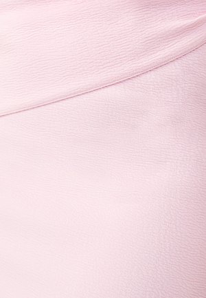Tessuto rosa chiaro con una superficie strutturata. Il materiale si drappeggia dolcemente, presentando un sottile motivo a onde e un design dell'orlo arrotondato.