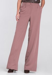 Spodnie o szerokich nogawkach w delikatnym różowym kolorze, wykonane z gładkiego materiału. Posiadają przednie kieszenie, zapięcie na guzik oraz dopasowany krój.