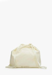 Bawełniany worek sznurkowy w kolorze kremowym, o miękkiej teksturze. Posiada pasujące zapięcia na wstążkę oraz subtelne logo na dole.