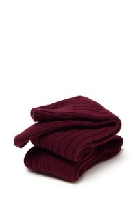 Calze in cotone bordeaux, caratterizzate da una texture a coste. Sono ripiegate con bordo curvo, mostrando un morbido materiale di lana.