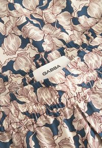 Stoff mit floralem Muster in Blau- und Cremetönen; verfügt über einen gerafften Bund und ein sichtbares Etikett mit der Aufschrift "GABBA."