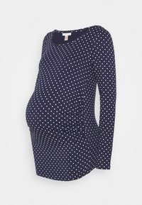 Laivansinis pitkähihaisen äitiyspaidat, joissa on valkoisia pilkkuja, curvat sivut ja pyöreä pääntie.