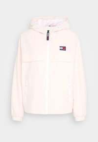 Jasnoróżowa lekka kurtka z kapturem, zapinana na zamek z przodu, z elastycznymi mankietami i naszywką z logo. Posiada dwie kieszenie boczne na zamek oraz siateczkową podszewkę.