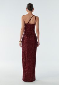 Burgundy sequined dress with a fitted silhouette, spaghetti straps, and a floor-length design, featuring a smooth texture and shine.