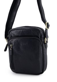 Černá kožená kabelka přes rameno s texturovaným povrchem, která má přední kapsu na zip, nastavitelný popruh a decentní značkování.