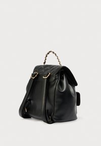 Μαύρο δερμάτινο σακίδιο πλάτης με υφή καπιτονέ, χρυσούς μεταλλικούς εξαρτήματα, διπλούς ιμάντες ώμου και χειρολαβή με αλυσίδα.