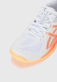 Løbesko i hvid mesh med orange og pink accenter, prydet med et struktureret mønster, gummisål og snørebåndsdesign.