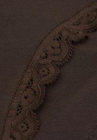 Bruine stof met een gestructureerde kanten rand met ingewikkelde patronen en een geschulpte rand. Over het algemeen een gladde textuur, met contrasterende details.