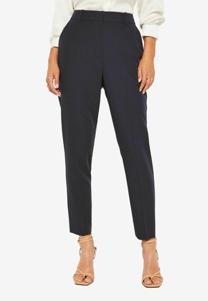 Marineblaue, taillierte Hose mit Slim-Fit, flachem Bund, Seitentaschen und Knöchellänge, kombiniert mit beigen, riemchen Sandalen.