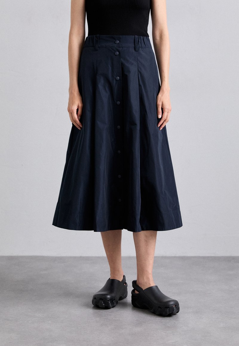 Jupe évasée bleu marine en tissu léger, dotée d'une fermeture à boutons sur le devant, d'une taille élastique et d'une texture douce et mate.