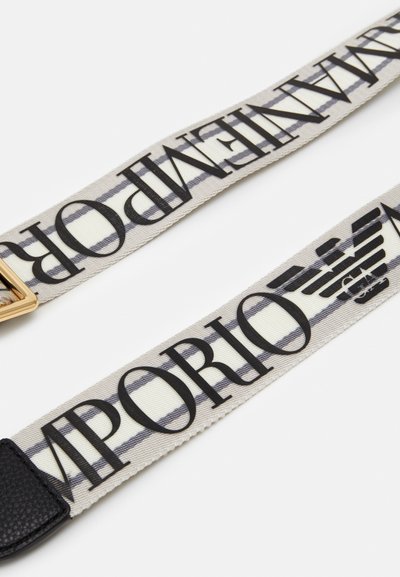 Vævet stofbælte med beige og hvide striber, sort tekst og en spænde i guldfarvet metal med logo detaljer. Holdbart og stilfuldt design.