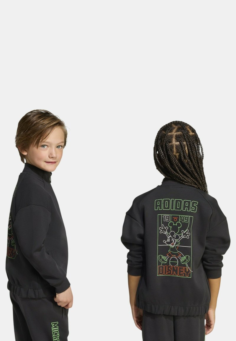 Felpa nera con grafiche verdi che raffigurano Topolino e testi, inclusi "ADIDAS" e "DISNEY," sul retro. Texture morbida.