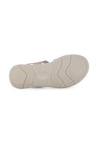 Sandal outsole in light beige rubber with textured grip, featuring a wave pattern and brand logo. Designed for traction and comfort.