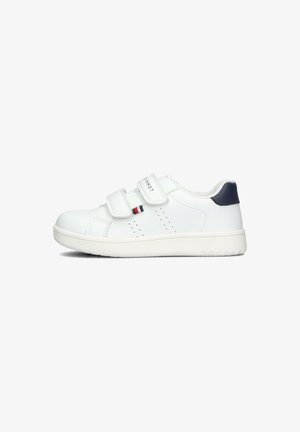 White sneaker with two Velcro straps, perforated detailing, and a navy accent at the heel. Smooth synthetic material and rubber sole.