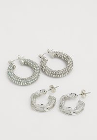 Četras sudarītās sudraba aļļu auskari: divi rotāti ar mirdzošiem rhinestones, viens ar teksturētu dizainu un viens gluds ar sarežģītiem akcentiem.