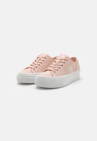 Light pink canvas sneakers with white rubber sole, featuring round toe, lace-up front, and a small white logo on the side.