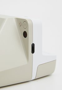 Casque avec un design beige et blanc, comportant un bouton d'alimentation, un indicateur lumineux et un port USB-C sur le côté.