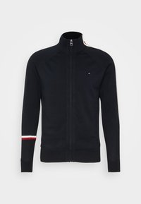 Felpa nera con zip, caratterizzata da un colletto alto, polsini a costine e strisce bianche e rosse sulle spalle. Realizzata in materiale a maglia testurizzata.