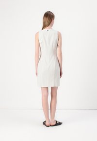 Hihaton, slim fit -mekko vaaleanharmaana, jossa on pystysuorat raidat. Koristenuppi takana. Sileä kangas, jossa on hillitty kiilto; polvipituinen.