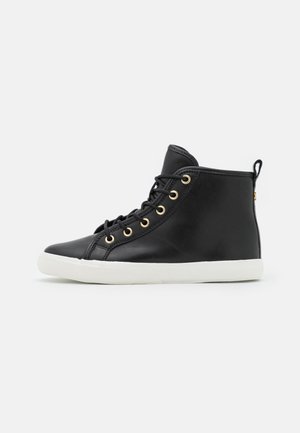 Schwarzer hoher Ledersneaker mit weißer Gummisohle, schwarzen Schnürsenkeln und goldfarbenen Ösen, seitlich auf einfarbigem Hintergrund dargestellt.