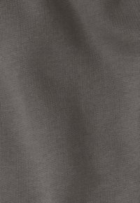 Tissu en tricot gris avec une surface texturée, présentant un motif côtelé fin. Le matériau semble doux et flexible.