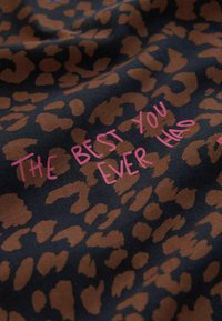 Tessuto marrone con stampa leopardata su sfondo scuro, con testo rosa che recita "THE BEST YOU EVER HAD." Aspetto morbido e texture evidente.