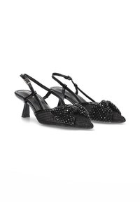 Tacones negros de slingback con un patrón texturizado, que presentan un lazo decorativo de cuentas en la parte delantera y un tacón bajo tipo bloque.